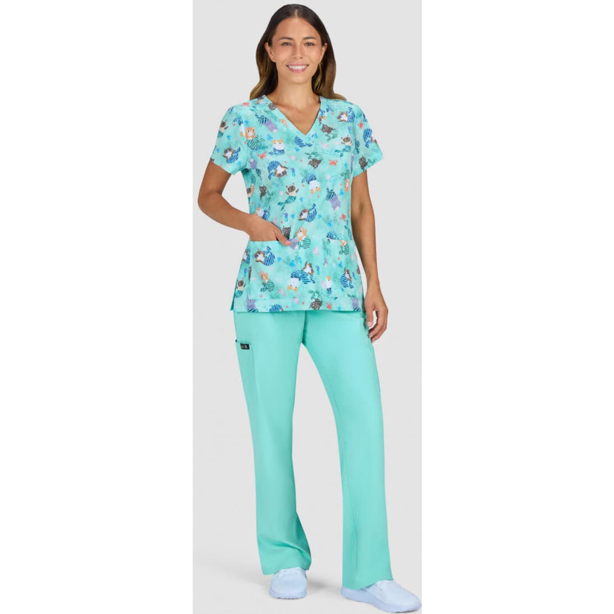 A floral print top in shades of teal, paired with matching teal pants, worn by a woman. The outfit includes a logo.