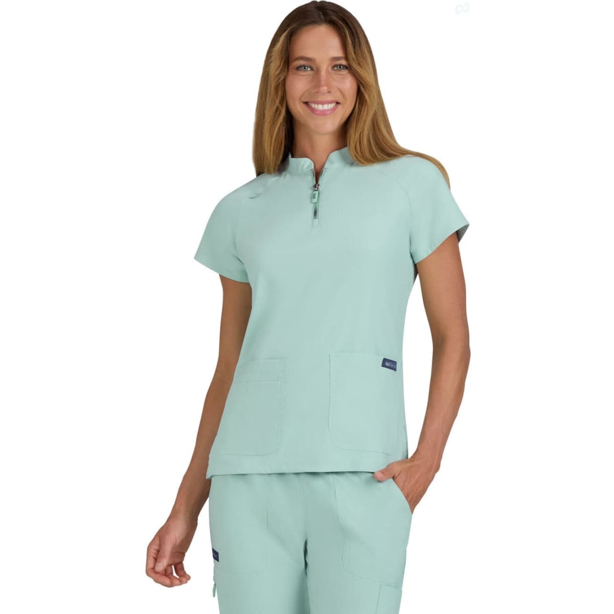 A limited edition scrub top in a soft mint green colour, featuring a zip neckline and two front pockets.