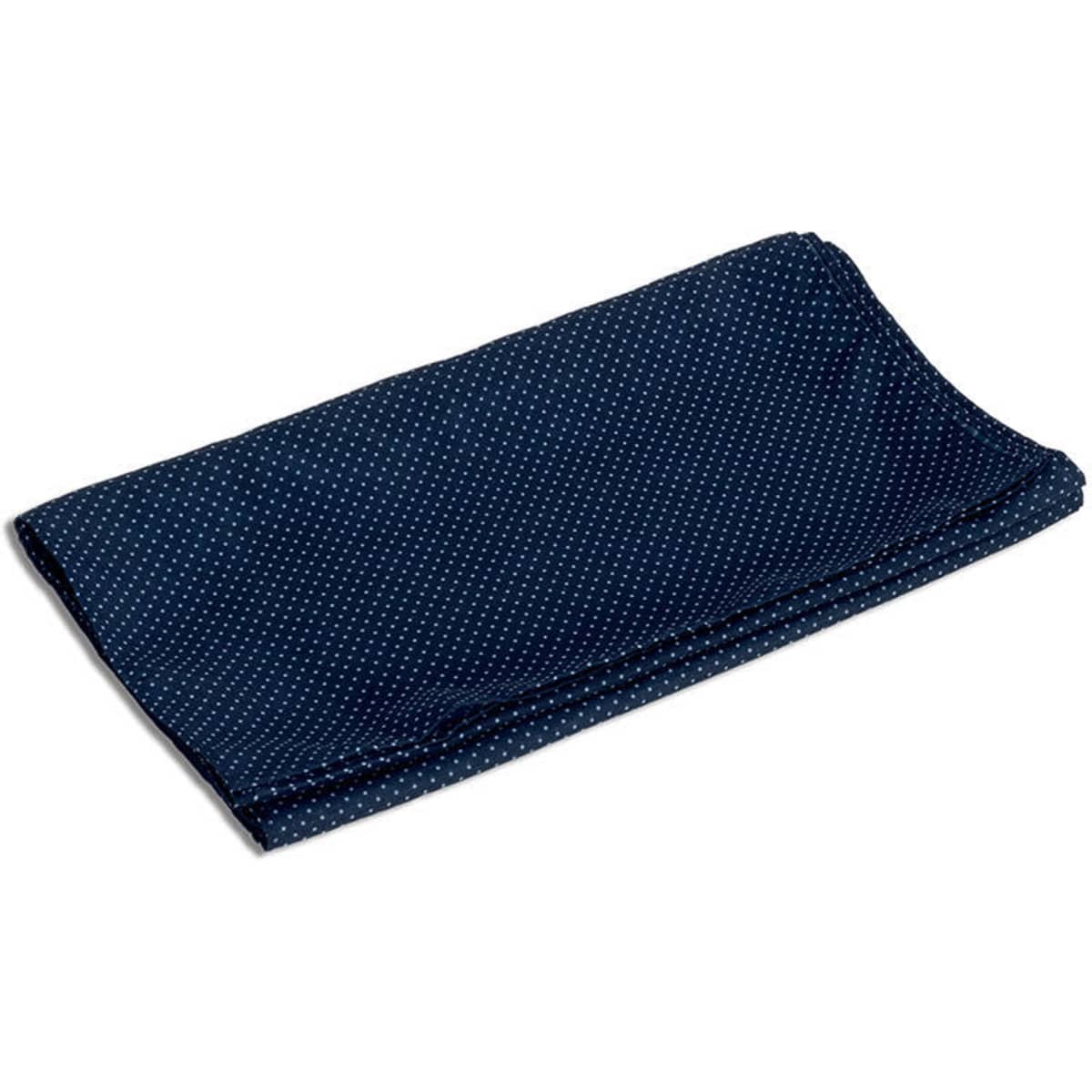 A folded neck scarf in navy blue with a white polka dot pattern, featuring a logo on one side.