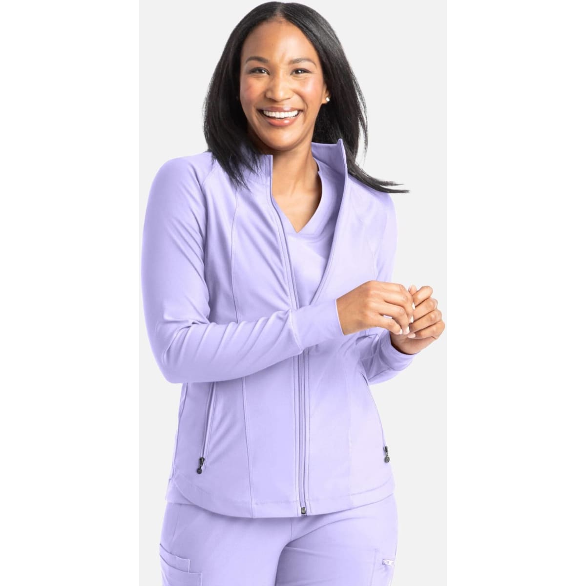A full zip track jacket in a soft lilac colour, featuring a stand-up collar and a logo. The model smiles while wearing it.