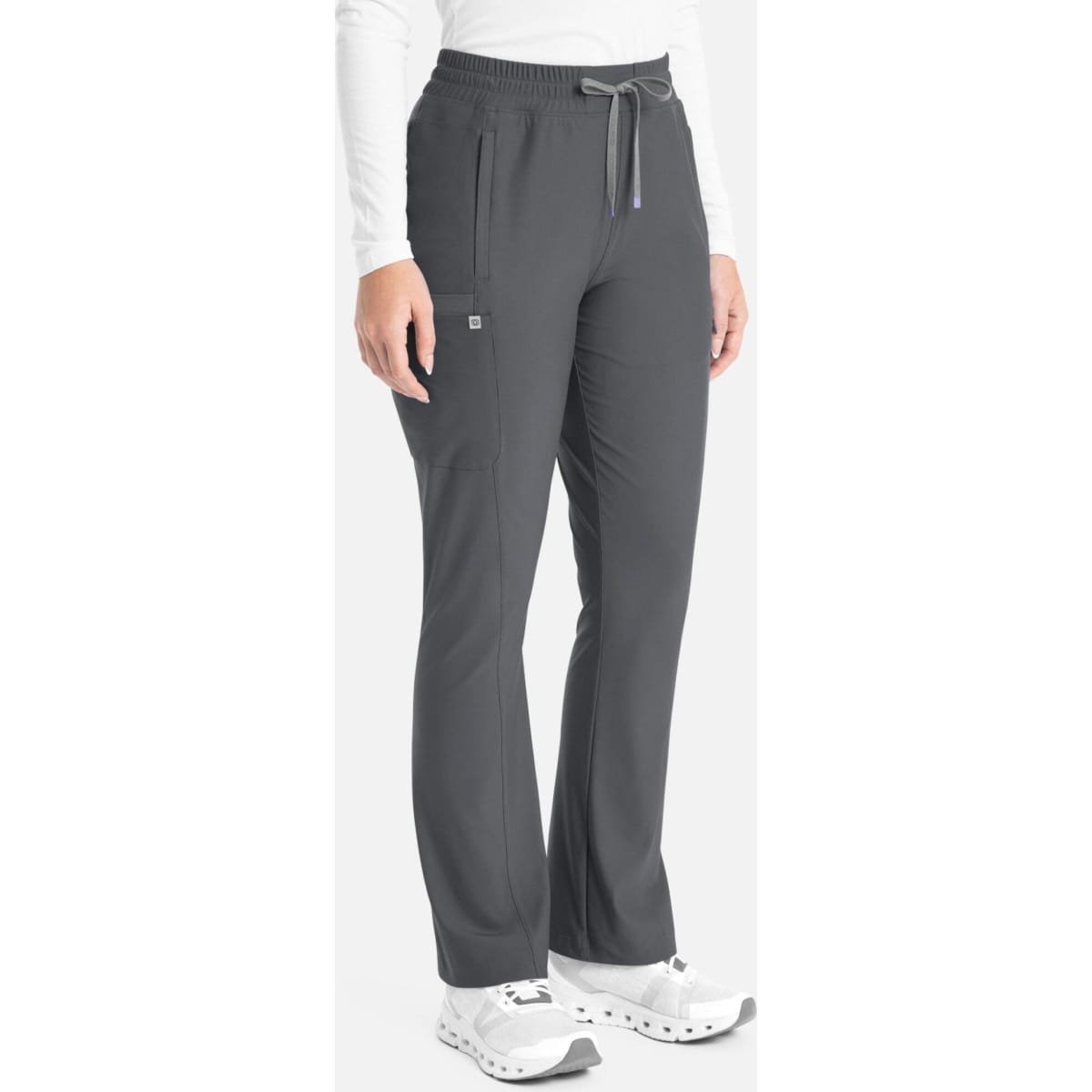 A woman is wearing dark grey bootcut pants with an elastic waistband and pockets, paired with white shoes.