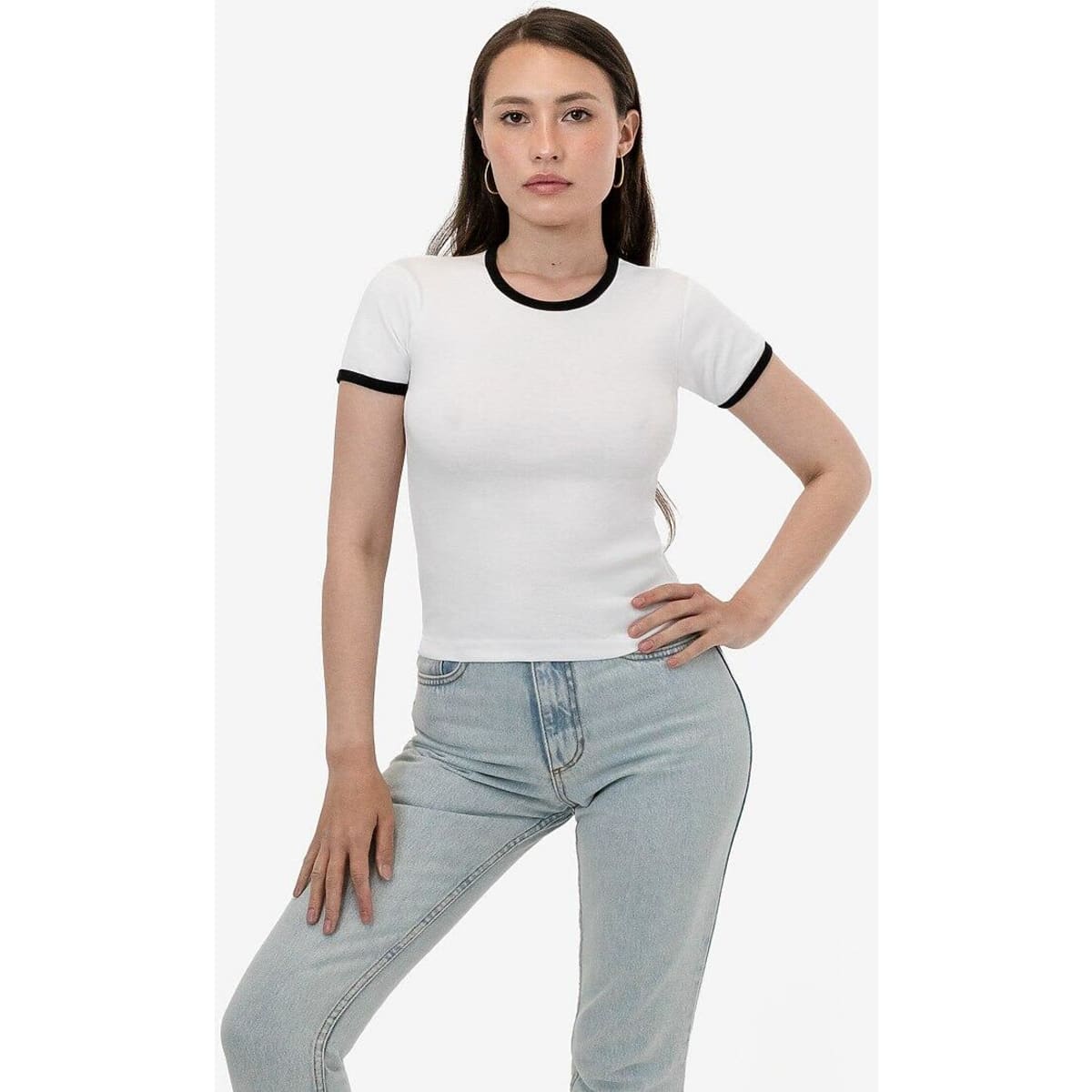 A fitted white baby rib tee with black trim, worn by a model posing in light blue jeans.