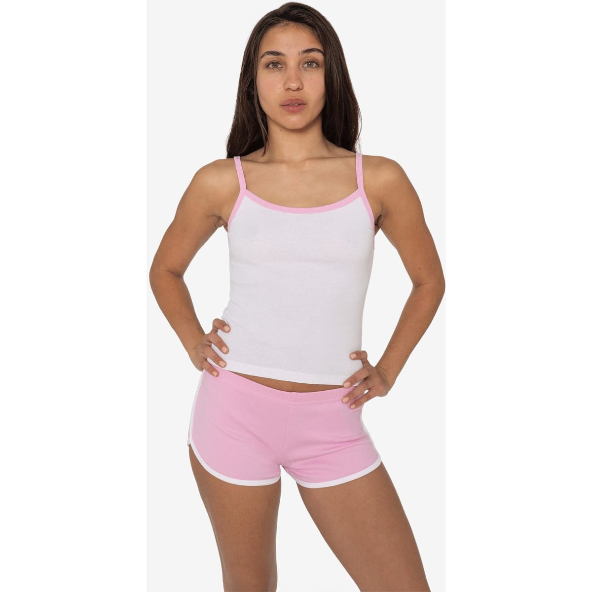 A model wearing a white spaghetti tank top with pink accents, paired with pink shorts, featuring a logo.