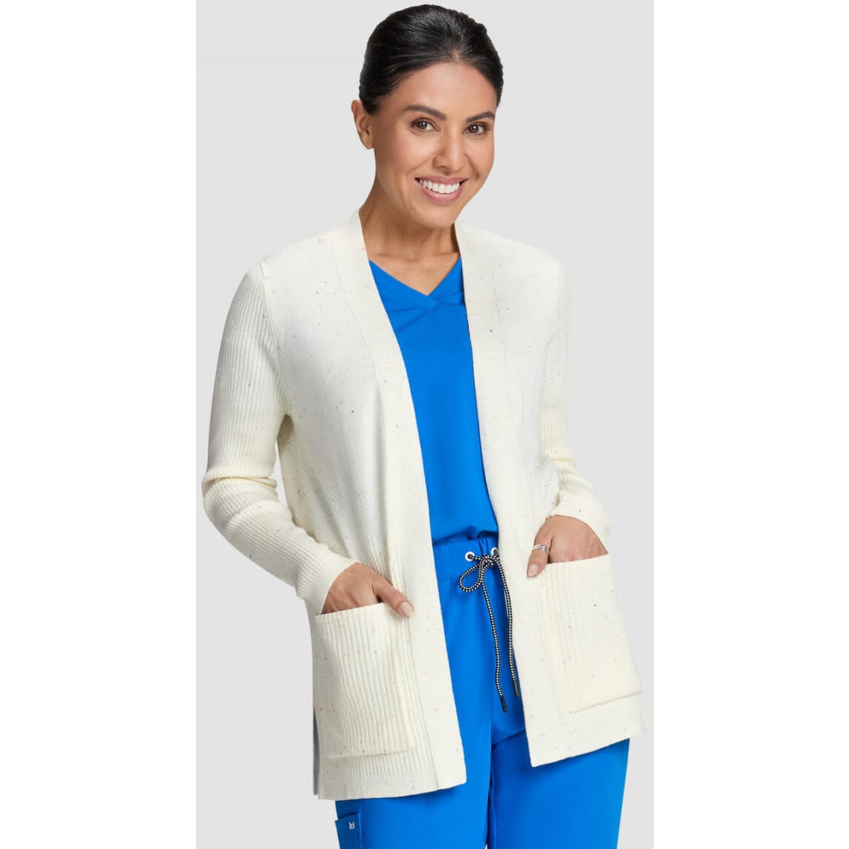 A cream Kori Sweater with a relaxed fit, featuring pockets and worn over a blue top.