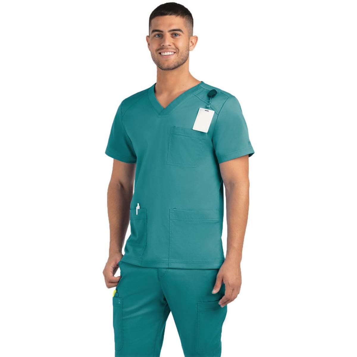 A men's teal v-neck top featuring three pockets, with a tag attached, modelled by a smiling man.