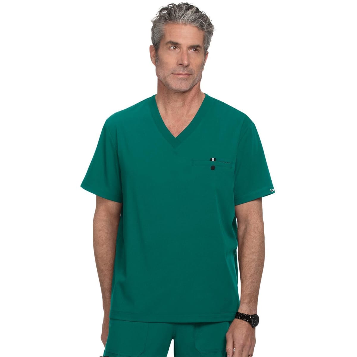 A teal V-neck scrubs top featuring a chest pocket and a logo on the sleeve. The model has grey hair.