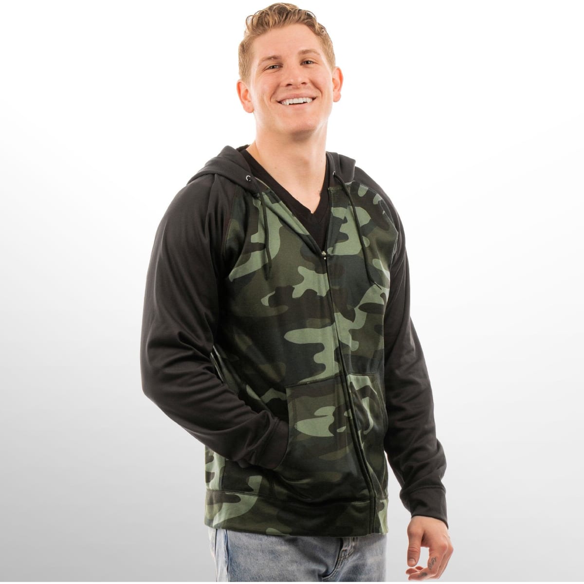 A camouflage and black Full Zip Performance Raglan Hoodie on a smiling model, featuring a hood and zip closure.