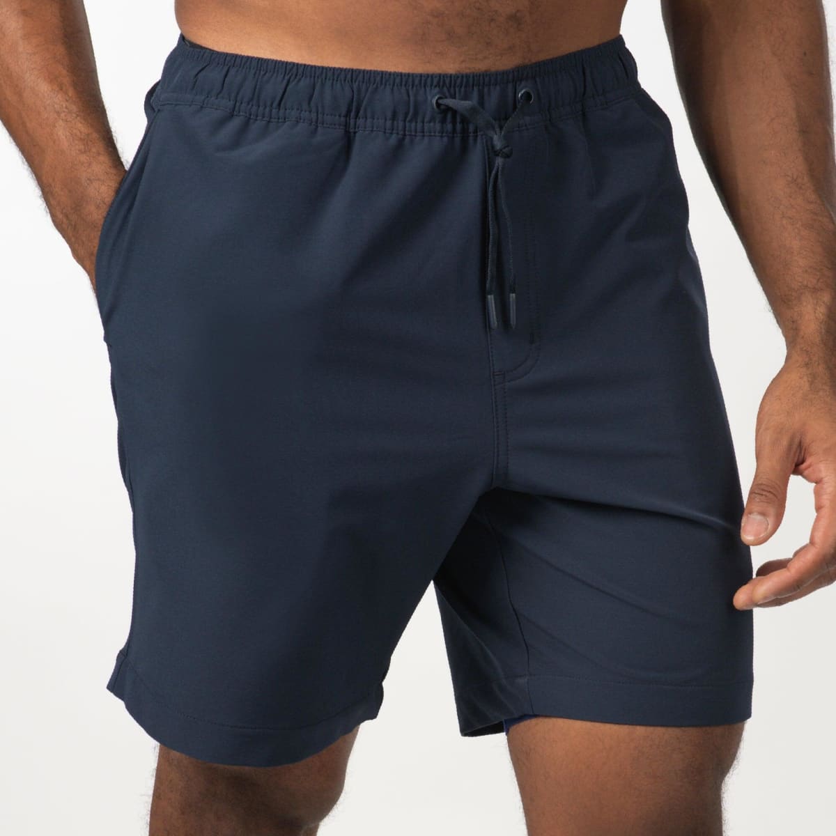 Navy sports shorts featuring an elastic waistband and a drawstring. Includes side pockets and a logo.