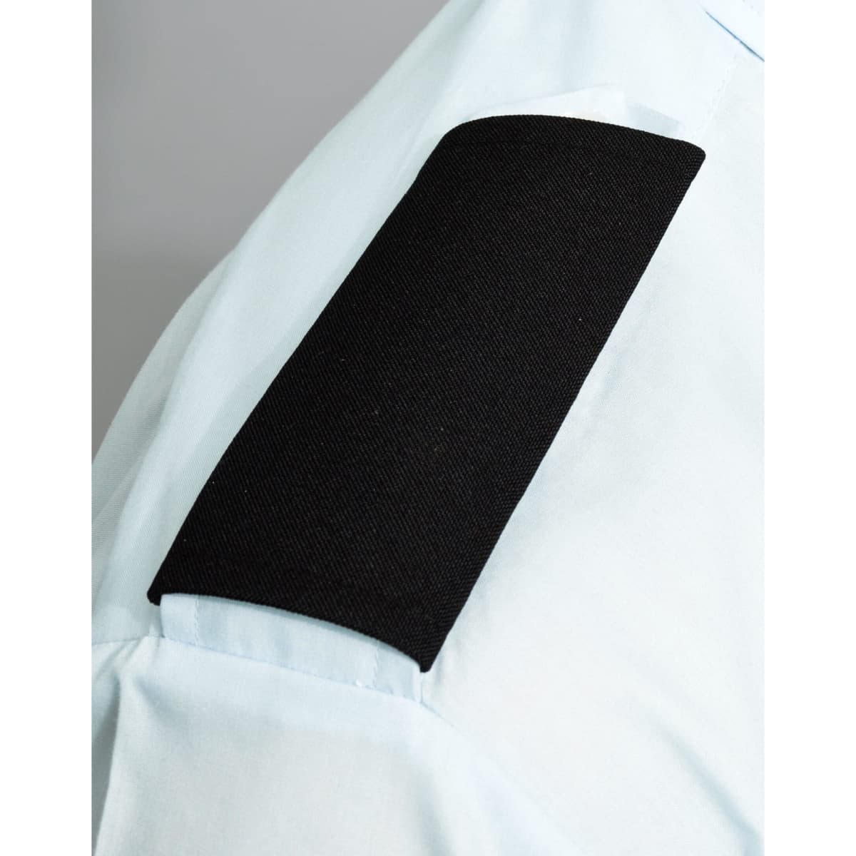 A light blue shirt with a black fabric epaulette on the sleeve, featuring a solid black section.