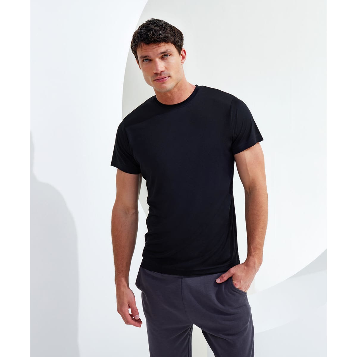 A black performance t-shirt displayed on a male model against a minimalist backdrop, showcasing its fit and style.