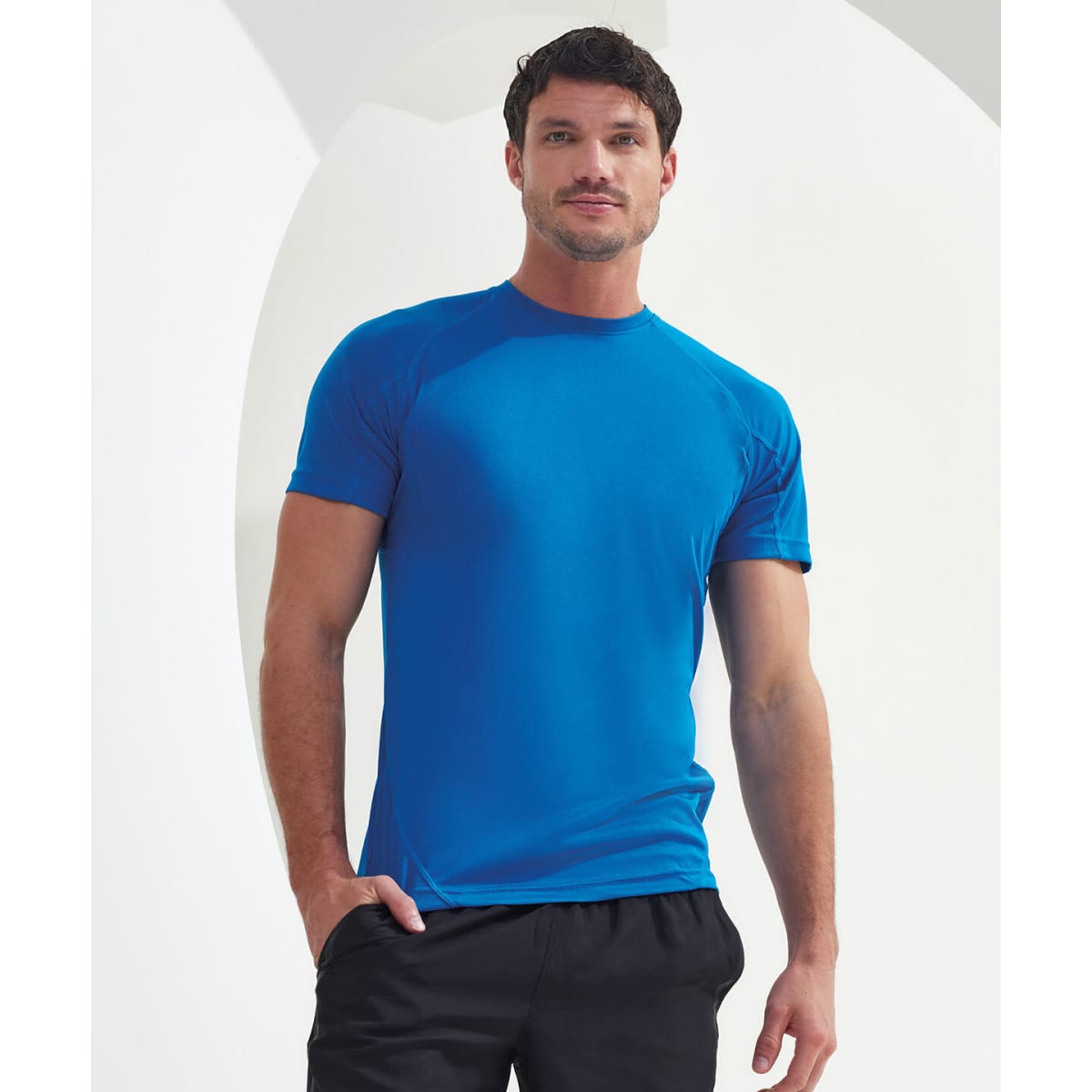 A panelled tech T-shirt in bright blue, featuring a fitted design and short sleeves. The model poses against a neutral background.