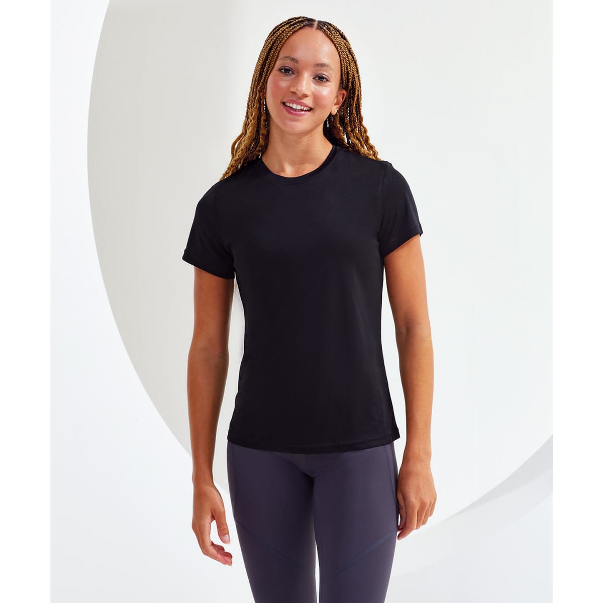 A black performance t-shirt displayed on a model with braided hair, featuring a round neckline and short sleeves.