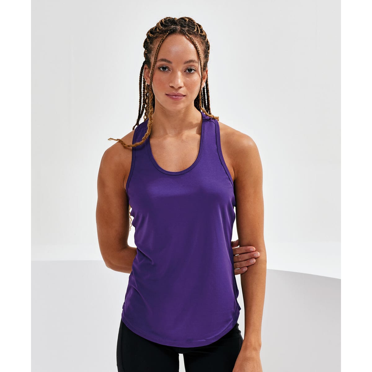 A purple performance strap back vest on a model with braided hair, posing against a neutral background.