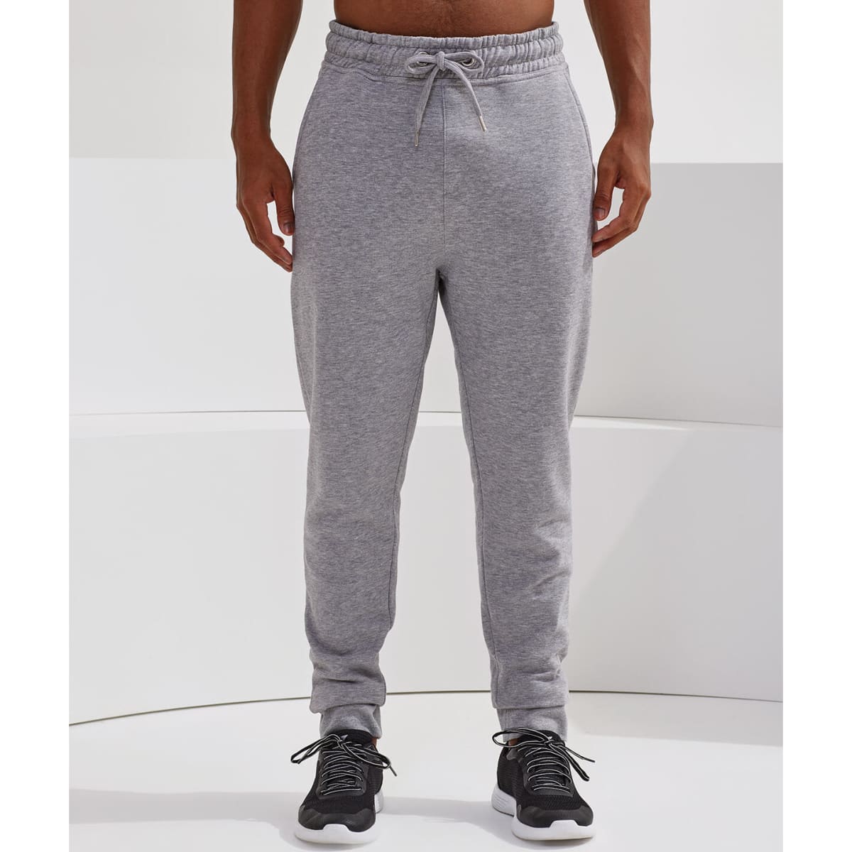 Fitted joggers in light grey, featuring an elastic waistband and a casual fit. The model wears dark footwear.