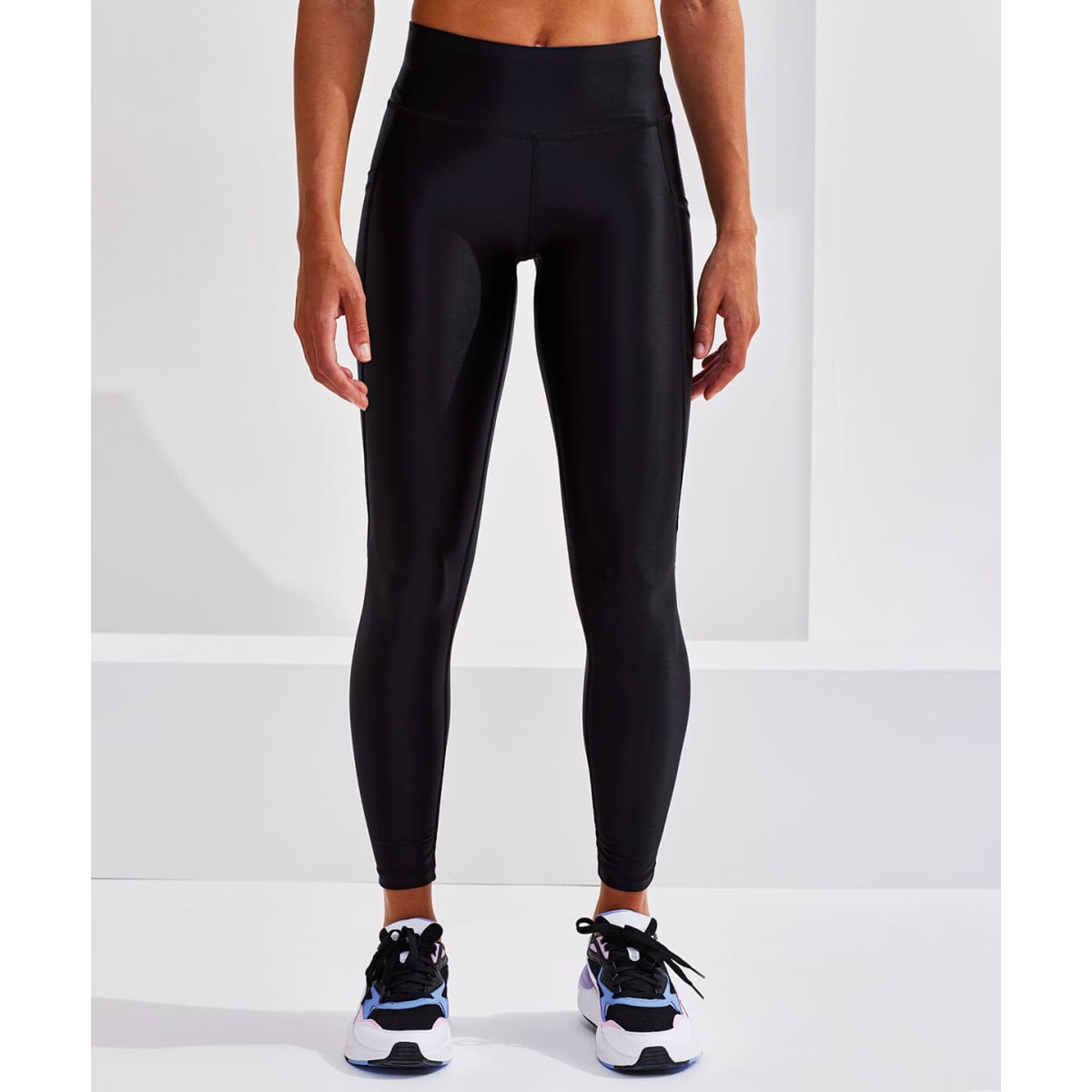 High-shine black leggings displayed on a model, showcasing a sleek and fitted design. The image includes a visible logo.