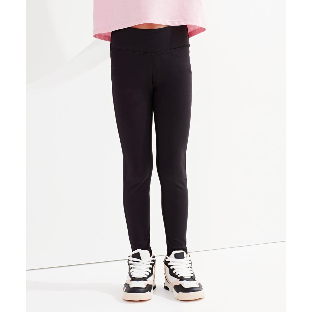 Black recycled performance leggings for kids, featuring a stretchy waistband and a fitted design, paired with sporty shoes.