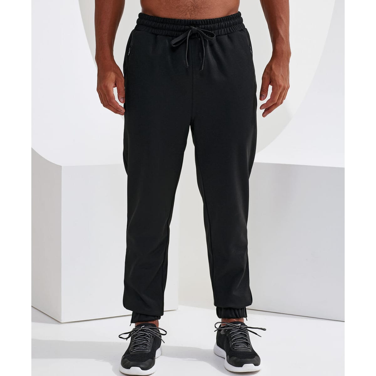 Black joggers with a tapered fit, featuring an elastic waistband and side pockets. Includes a logo on the fabric.