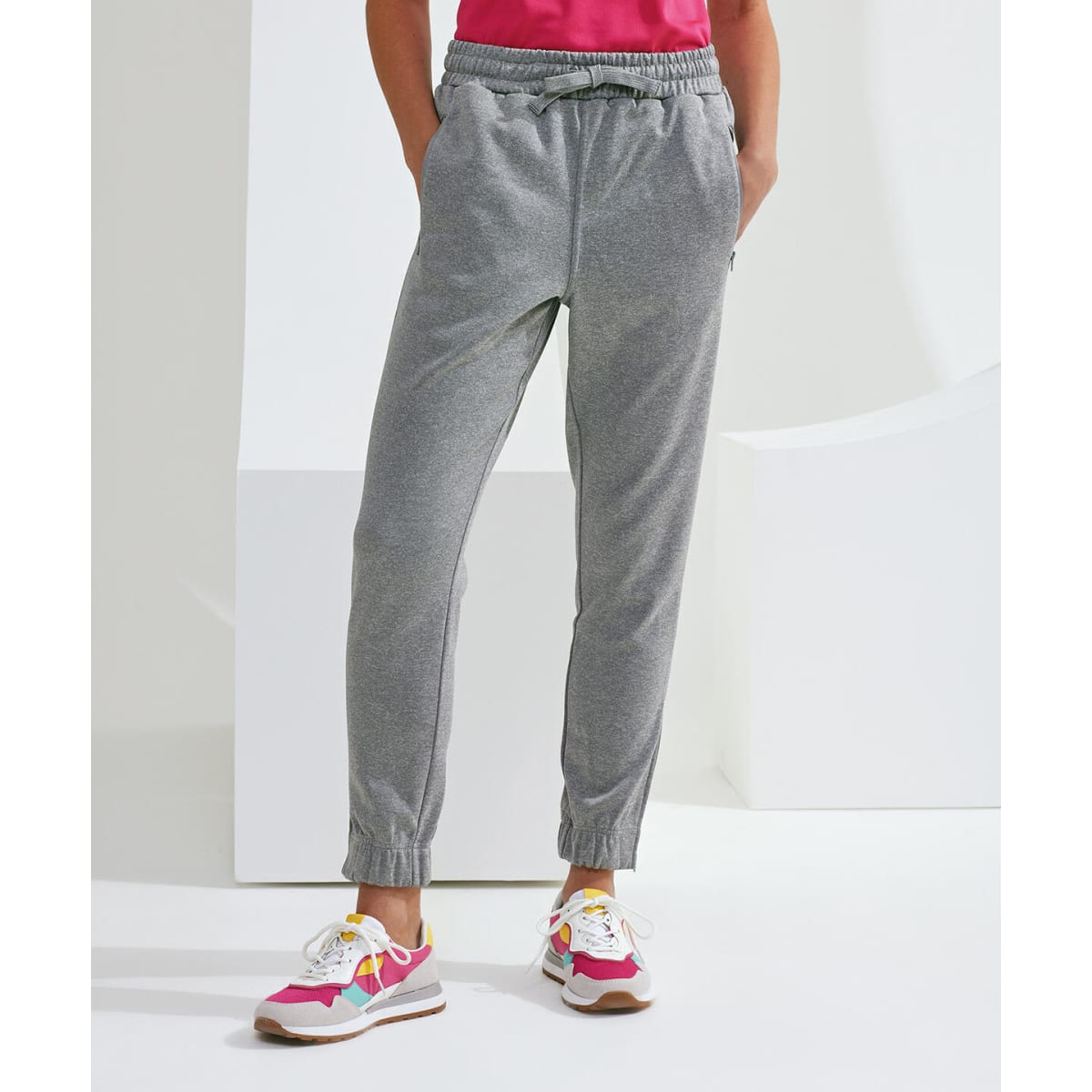 Grey joggers with an elastic waist and cuffs, featuring side pockets, worn with colourful athletic shoes.