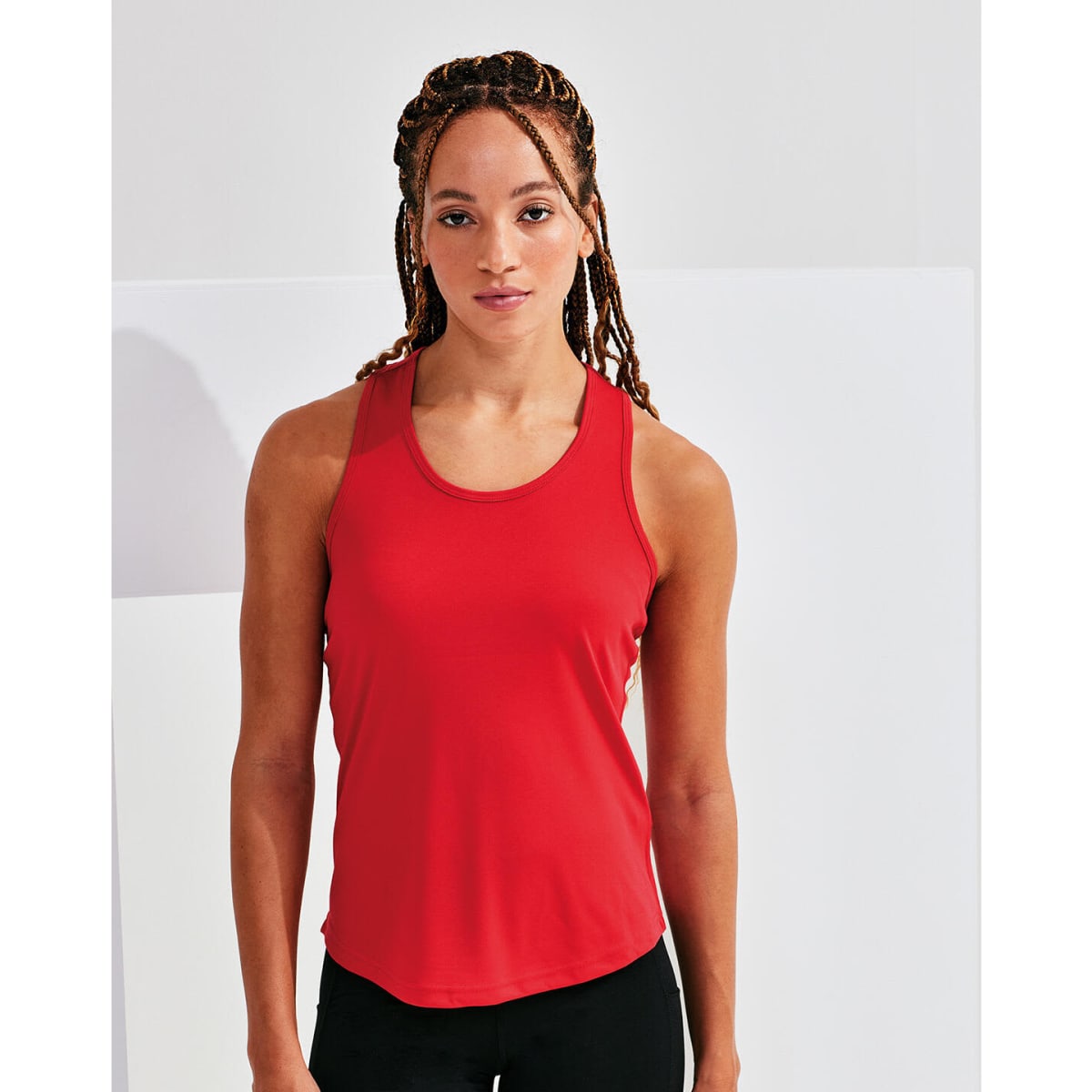 A red slim racerback vest, made from recycled materials, displayed on a model with braided hair.