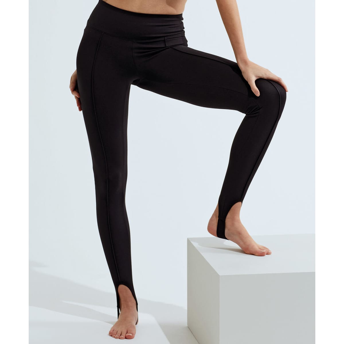 Black recycled fashion stirrup leggings displayed on a model, featuring a sleek design with stirrup details.