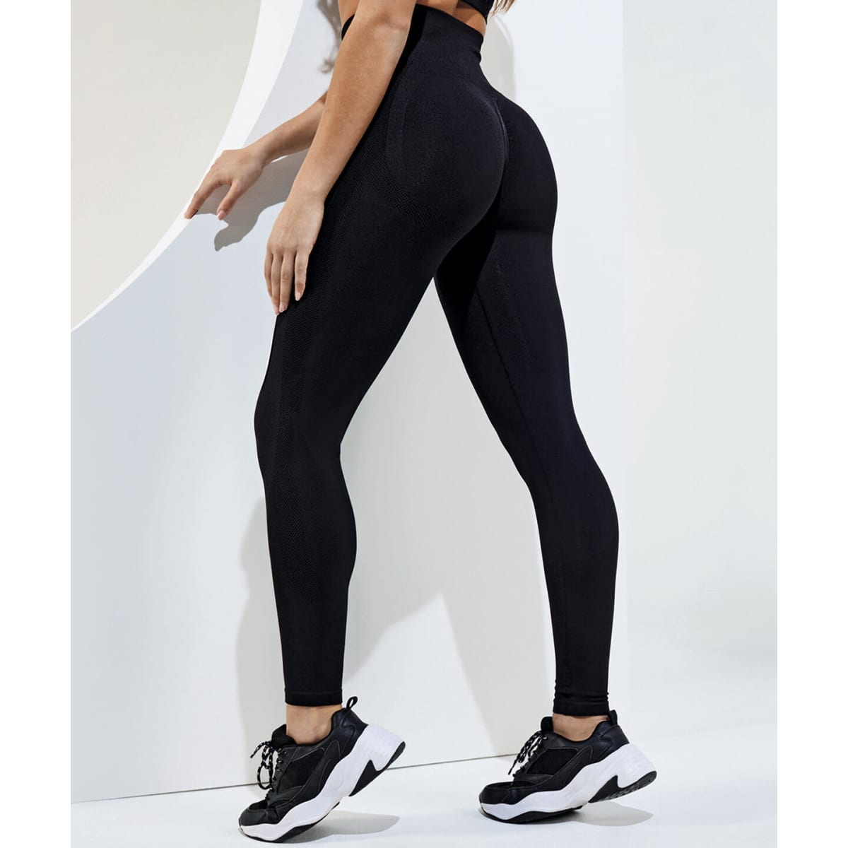 Black recycled scrunch leggings are displayed from the back, paired with black athletic shoes. The image features a logo.