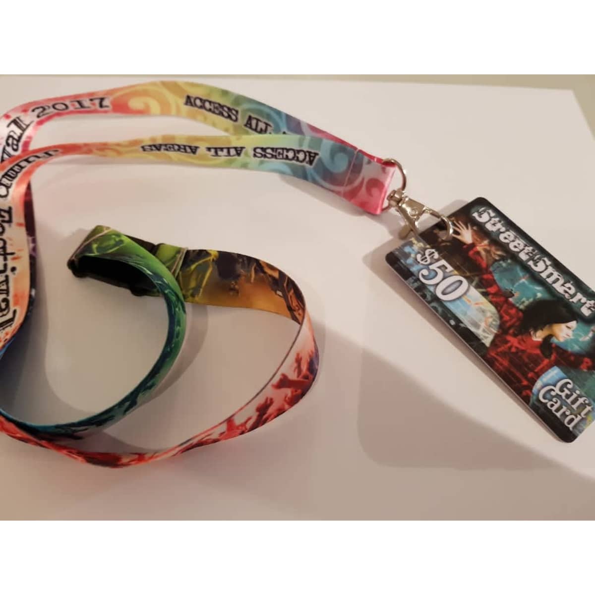 A full sublimated lanyard in vibrant colours with a card attached, featuring a logo and artistic design elements.