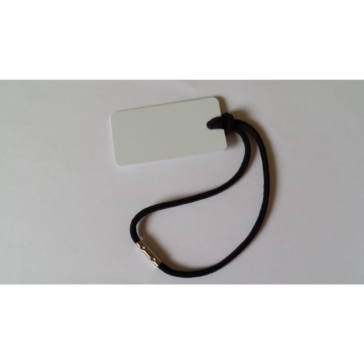 A black wrist cord with a rectangular white tag attached, suitable for lanyards or holding ID cards.