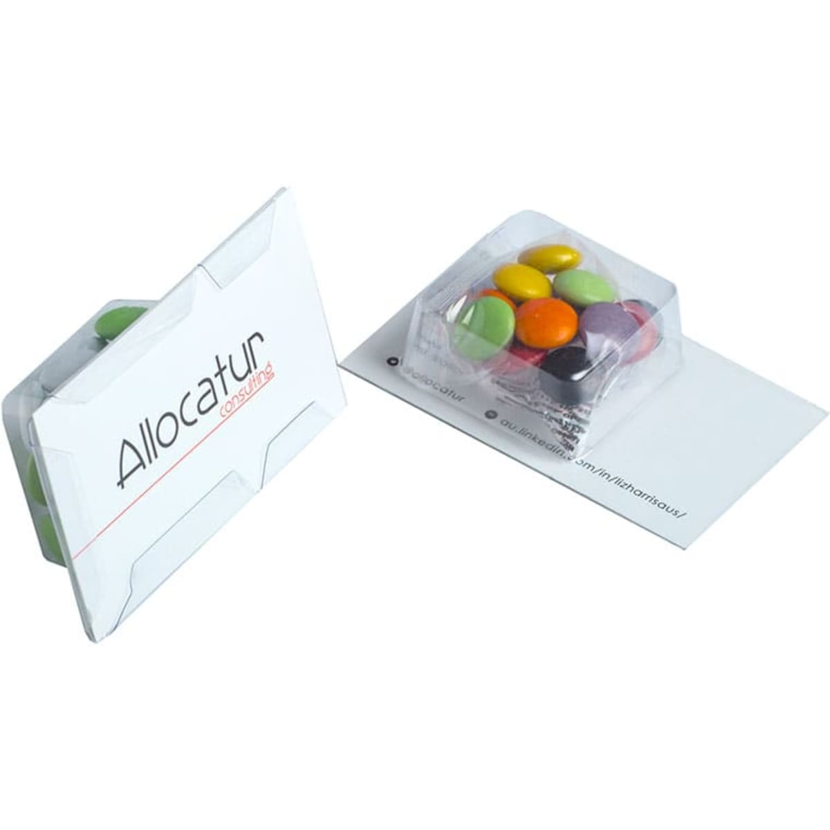 A white promotional card contains a clear plastic tray filled with colourful chocolate beans.