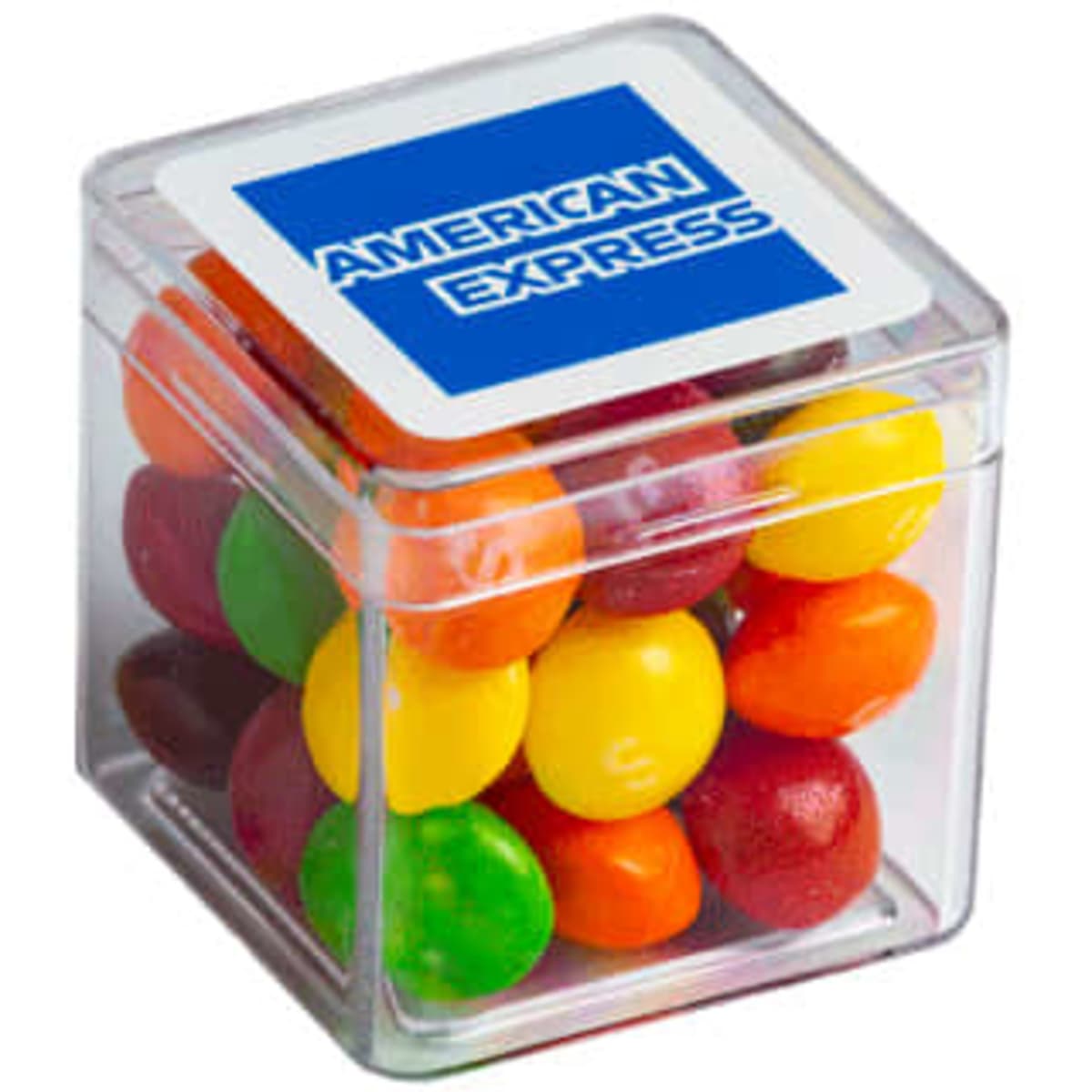 A transparent cube containing colourful Skittles in various shades, with a branding logo on the lid.