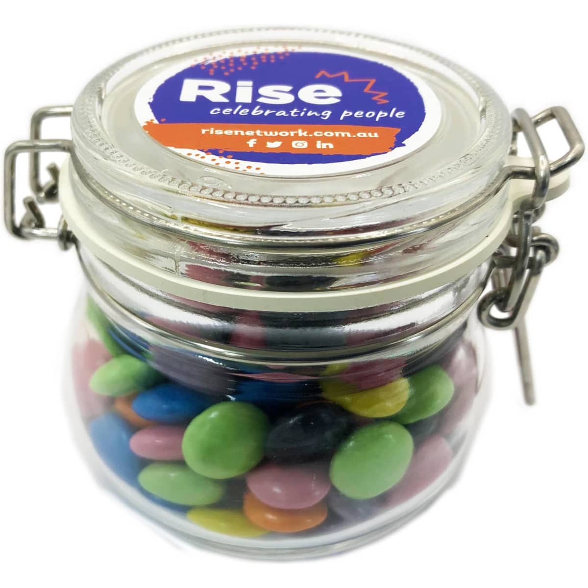 A glass canister filled with colourful choc beans, featuring a metal clasp and a branded lid.