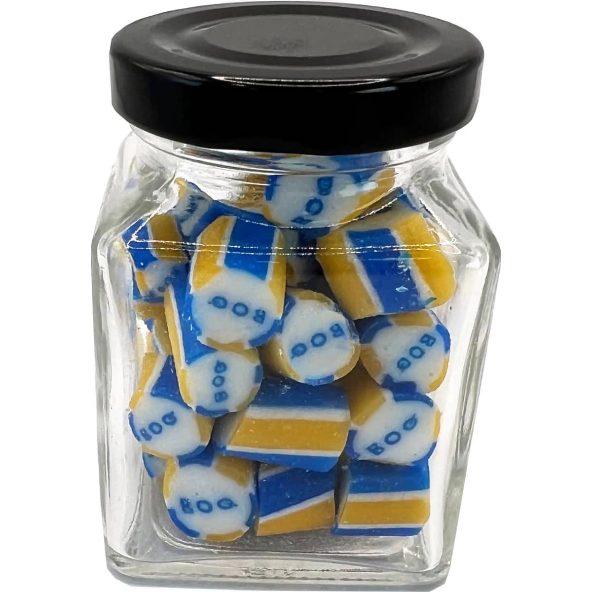 A small glass jar filled with blue and yellow rock candy pieces, featuring a black lid and a logo on the jar.