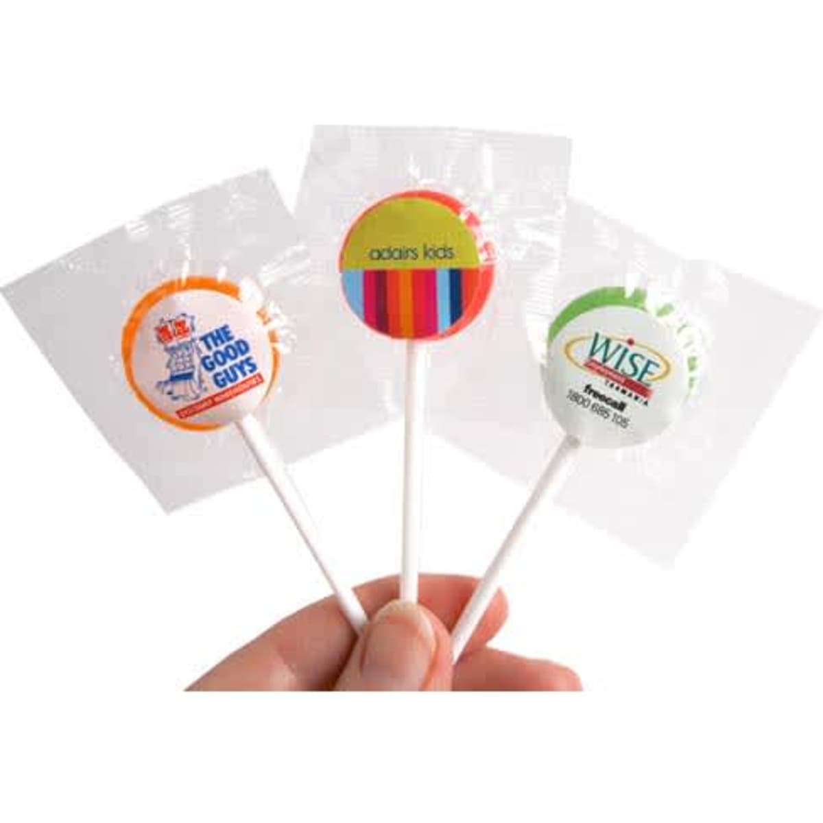 A hand holding three small lollipops with colourful branding on their wrappers.