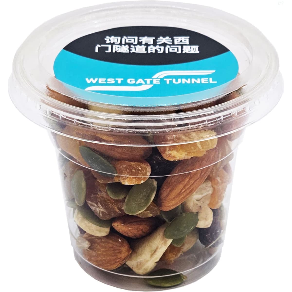 A clear cup filled with a mix of dried fruits, nuts, and seeds, featuring brown, green, and beige colours.