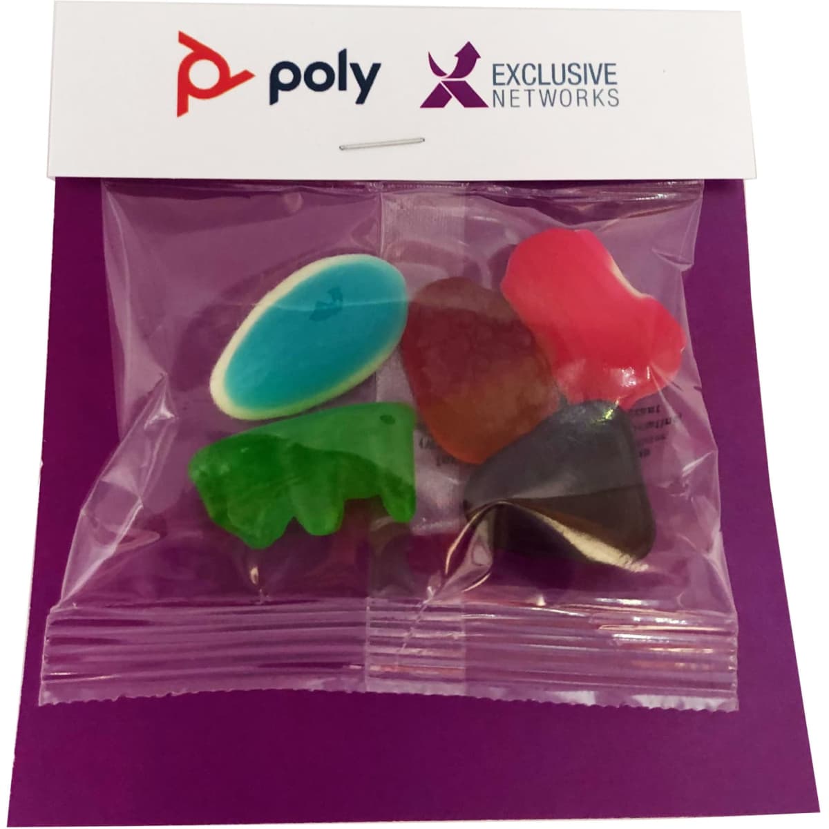 A bag containing mixed lollies in various shapes and colours, including blue, green, red, and purple. It has branding.
