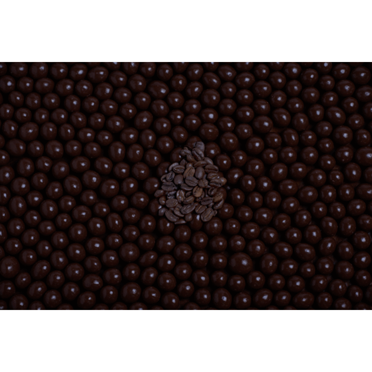 A cluster of dark chocolate-coated coffee beans arranged over a bed of more dark chocolate-coated beans.