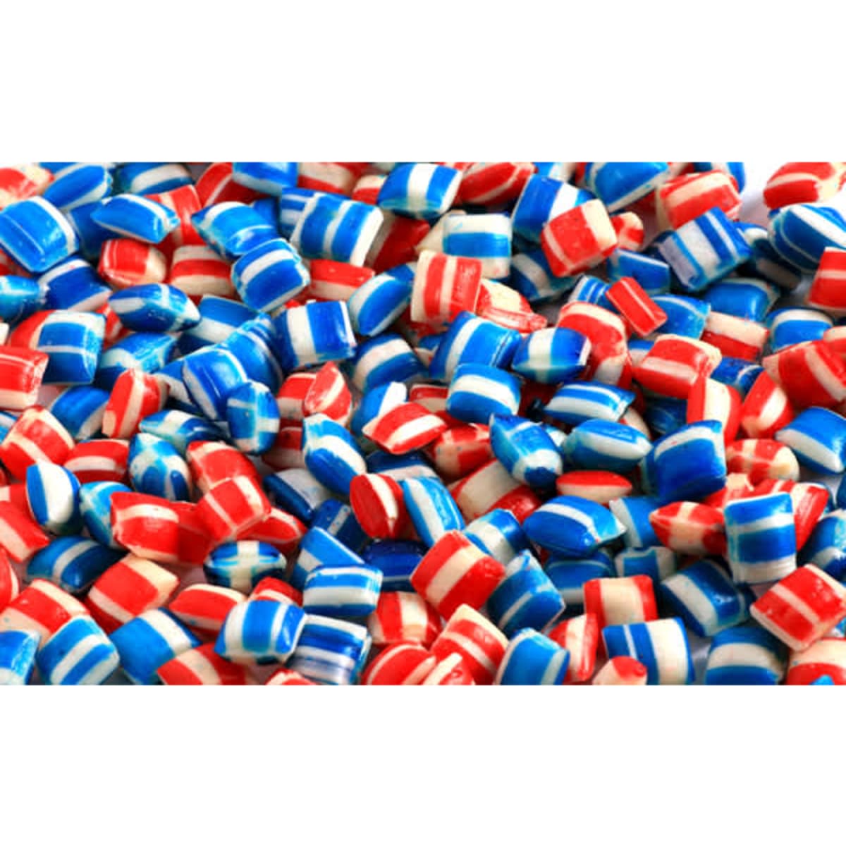 Colorful red, white, and blue mints scattered across a surface, featuring a shiny finish and various striped patterns.