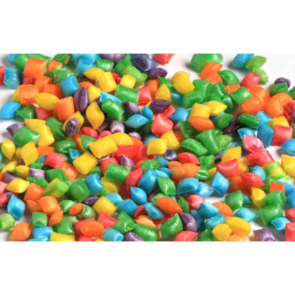 Colourful tiny mints in various shades of red, green, blue, yellow, and purple scattered on a white surface.