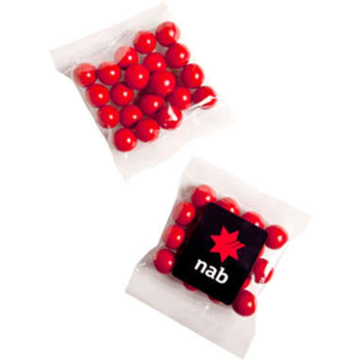 A clear packet containing red chocolate-coated treats and a small black square with a logo.