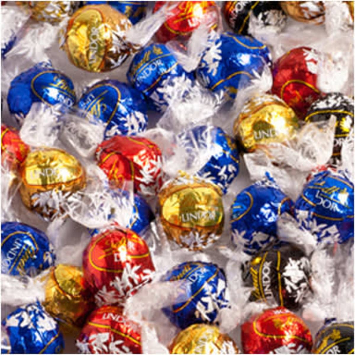 A collection of Lindor chocolate balls in red, blue, gold, and black wrappers, with some featuring a festive design.