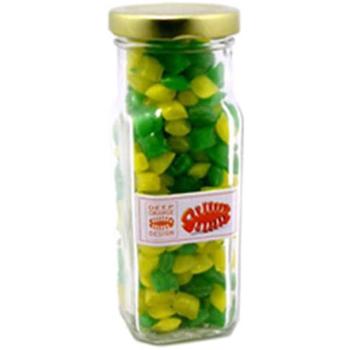 A tall glass jar with a gold lid, filled with green and yellow humbug sweets. The jar features a logo.