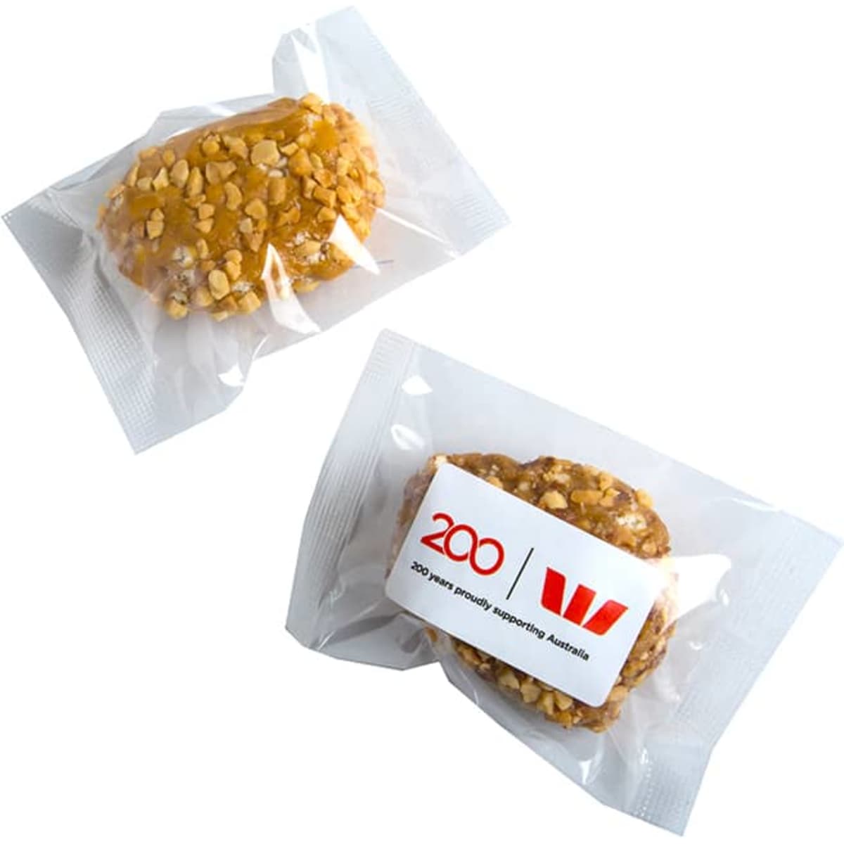 Two individually wrapped protein balls coated in crushed nuts, featuring a simple logo on the packaging.
