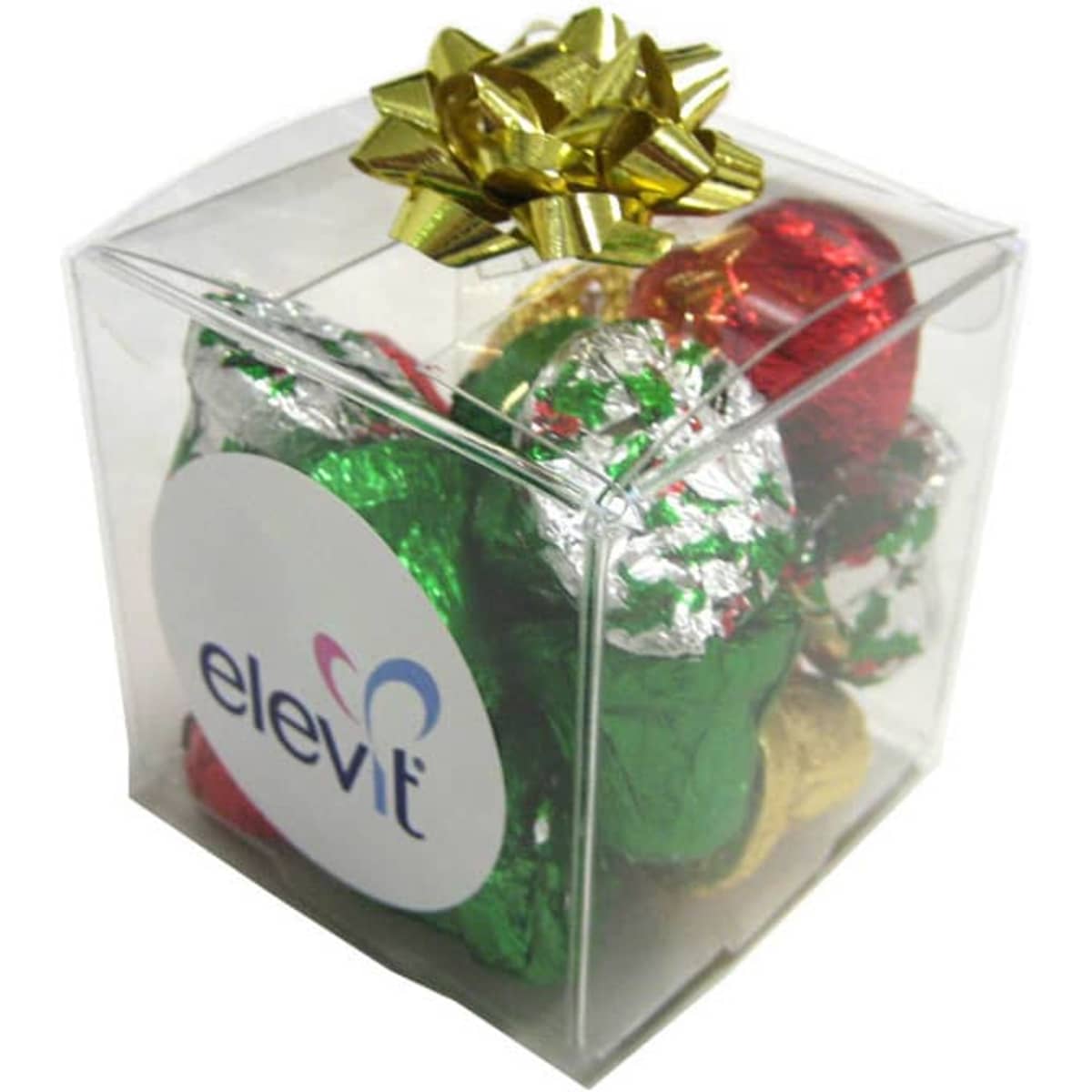 A clear cube filled with assorted Christmas chocolates wrapped in red, green, and silver foil, topped with a gold bow.