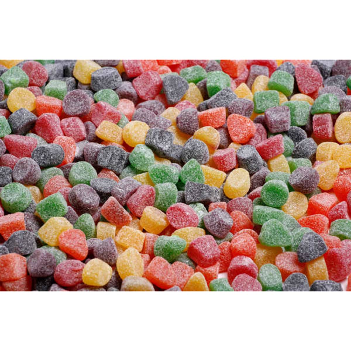 A variety of small, chewy gummi lollies in vibrant colours including green, red, yellow, purple, and orange, with a sugary coating.