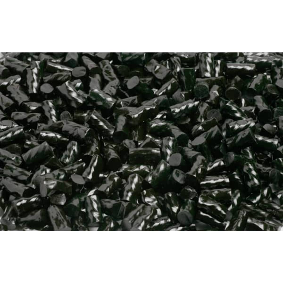 A close-up of glossy black liquorice pieces, in a variety of cylindrical shapes, with a shiny finish.