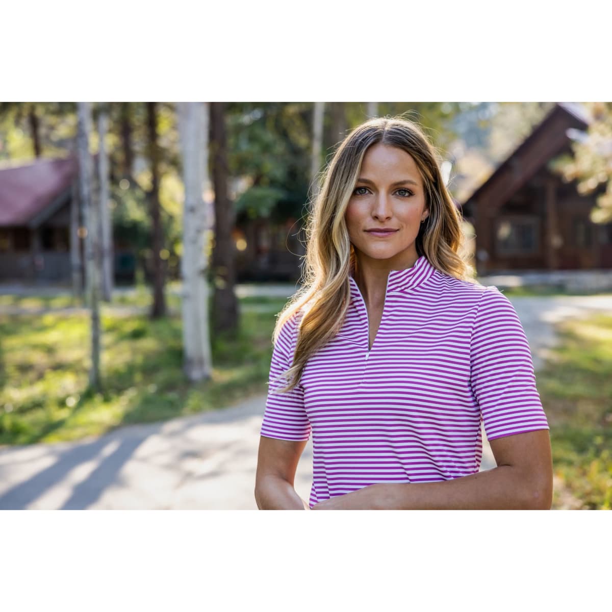A pink and white striped polo shirt featuring a high collar and short sleeves, with a visible logo.