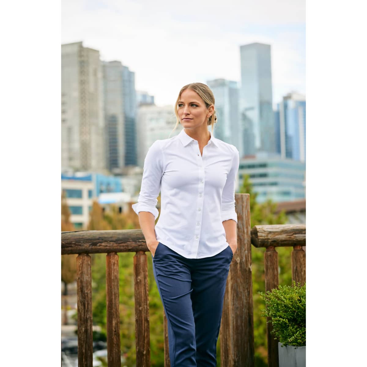 A white long-sleeve button-up shirt with a collar, paired with navy trousers, worn by a woman.