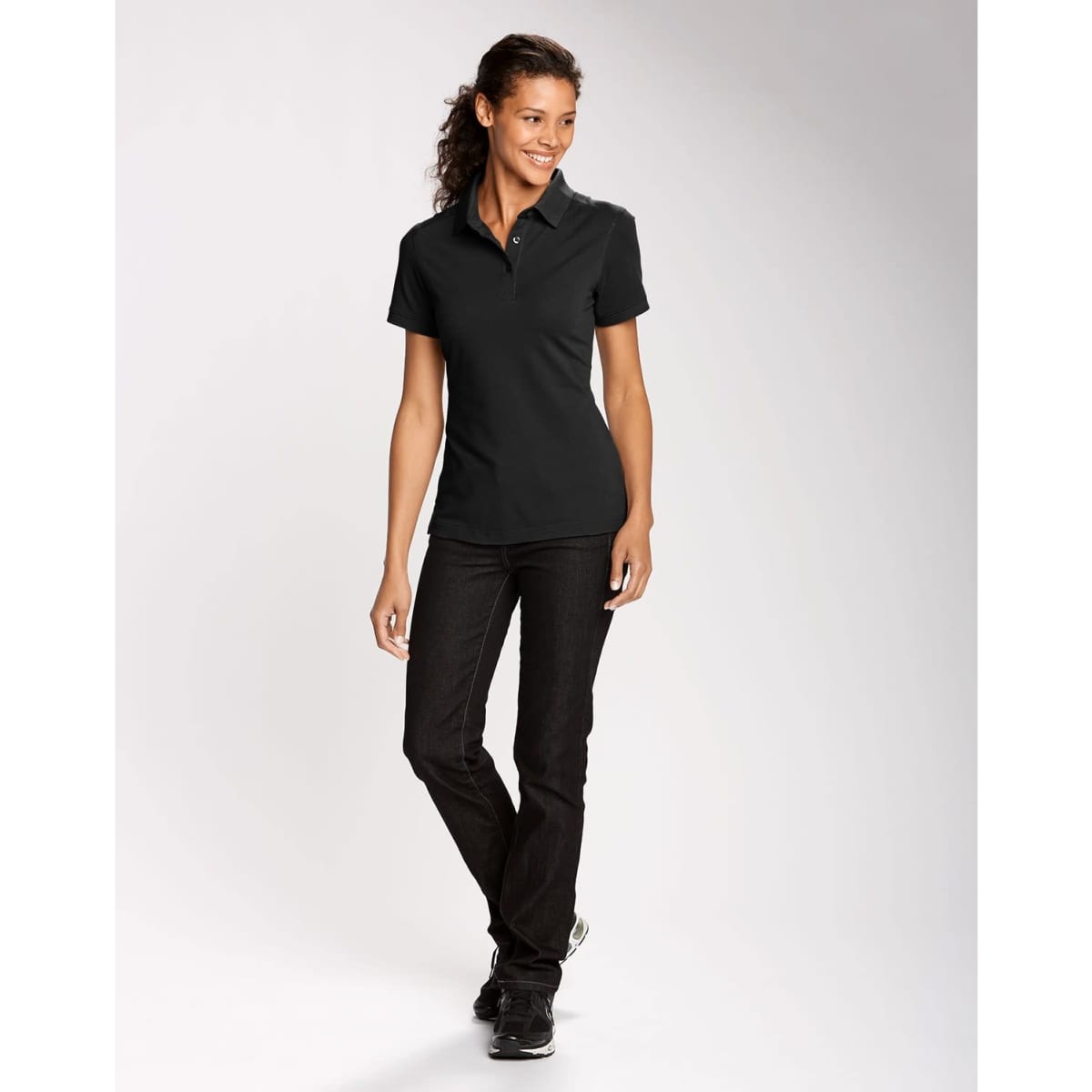 A black women's polo shirt paired with dark jeans, featuring a collar and a logo.
