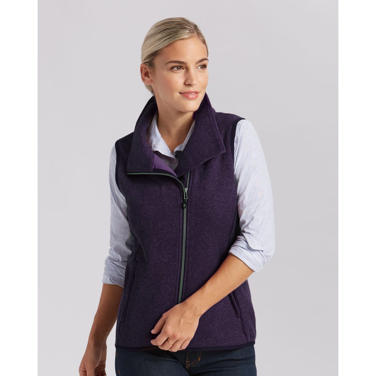 A purple ladies vest featuring a high collar and front zip, worn over a striped shirt. Includes a logo.