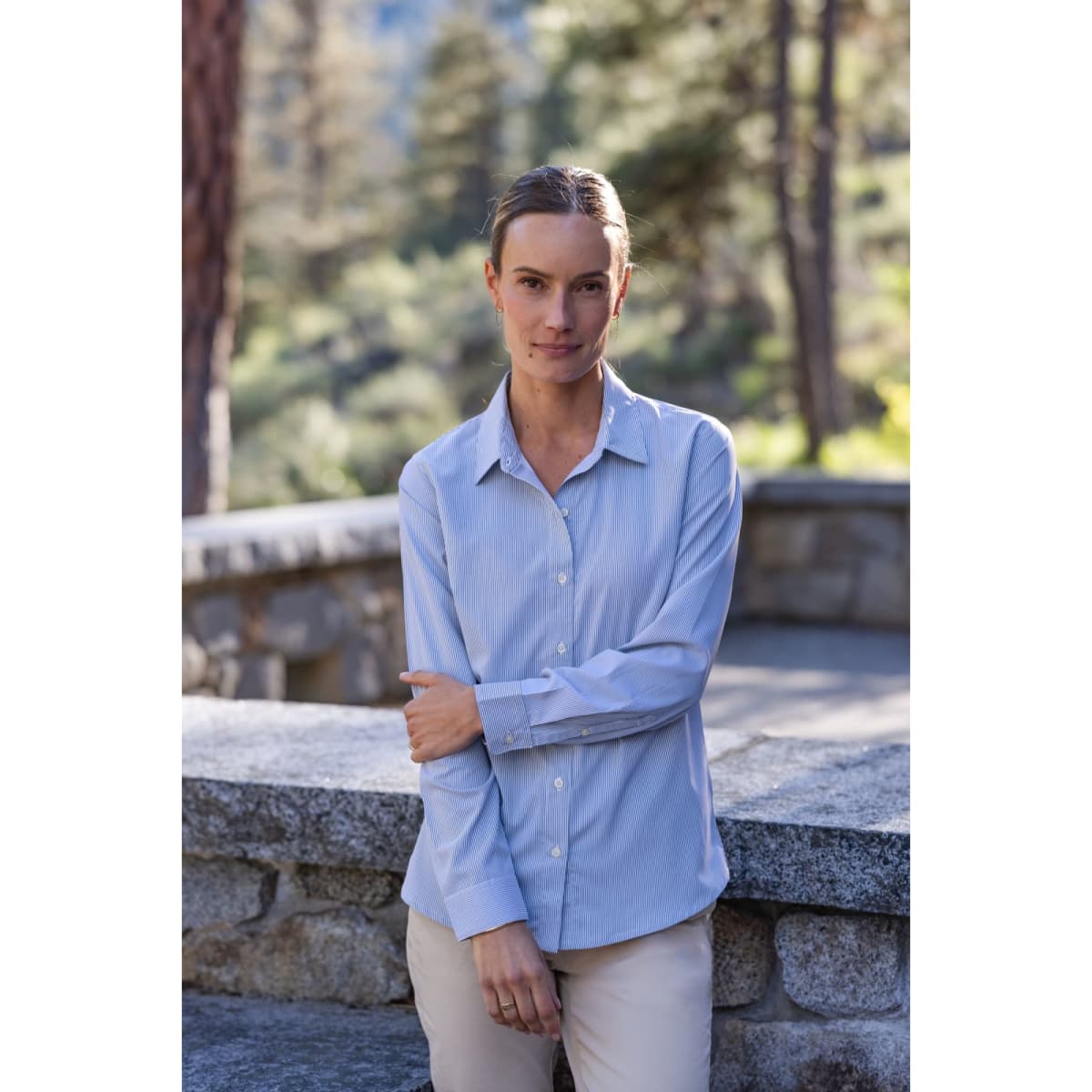 A light blue ladies' shirt with a pinstripe pattern, featuring long sleeves and a collar, displayed outdoors.