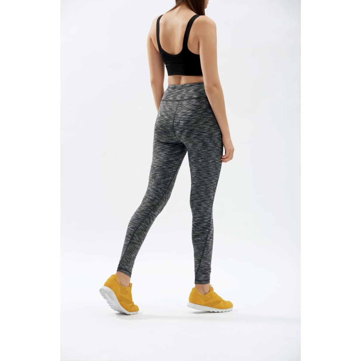 Ladies' active leggings in space dye pattern, featuring a black and grey design, paired with yellow athletic shoes.